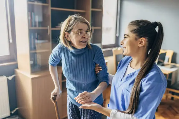 Photo of A nurse and a senior woman practice moving around the house