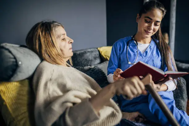 Photo of A nurse is reading a book to a senior patient