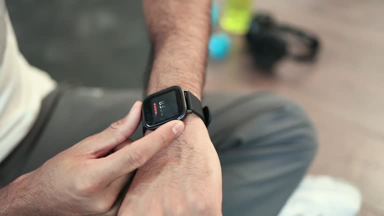 Sporty man checking pulse on smartwatch after workout inside