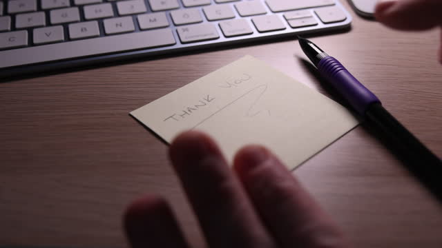 Man writes thank you on sticky paper