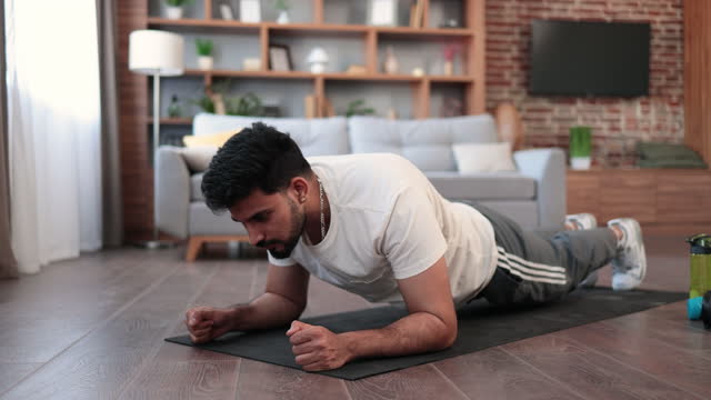 Arabian male athlete doing plank exercise at home