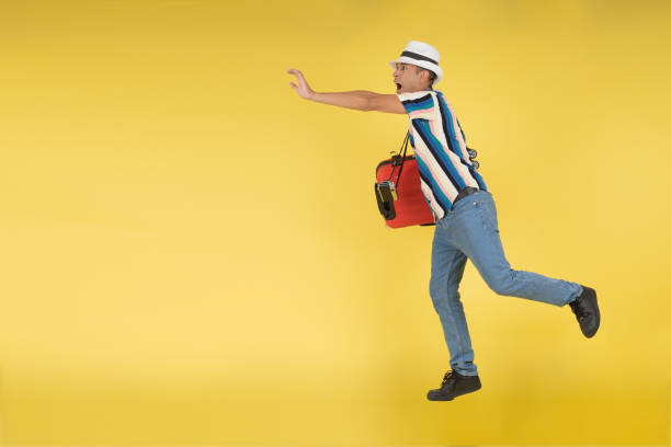 istock Young man, scared running because he is going to be left by the plane, with his red carry-on suitcase under his arm 1478873746