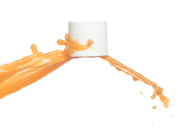 istock Orange Juice moisturizer lotion cream pouring down in cosmetic bottle container. Orange paint beauty lotion fluttering explosion in air, splash spill like explosion droplet. White background isolated 1478879907