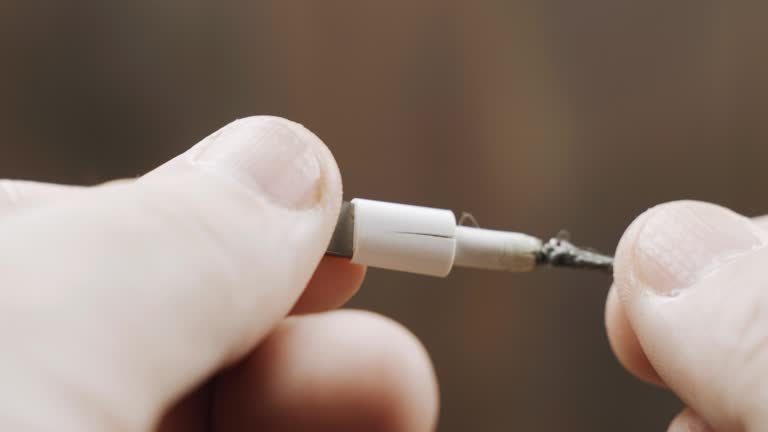 Old charger cable is broken, close-up of broken white insulation.