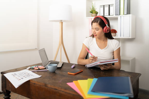 istock Young woman listening to the lesson with her headphones while taking notes in her notebook 1478887991