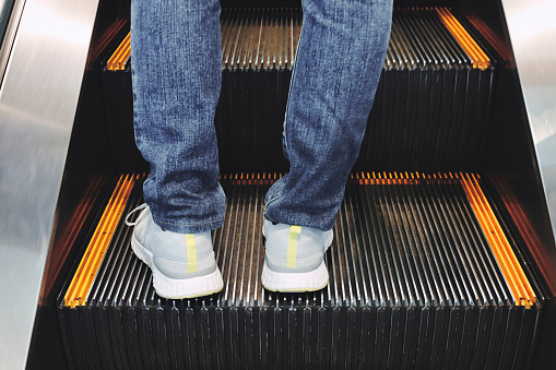 Woman in jeans riding an escalator