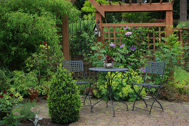 Backyard patio with rich foliage and furniture Cozy little back yard terrace with table and chair. trellis photos stock pictures, royalty-free photos & images