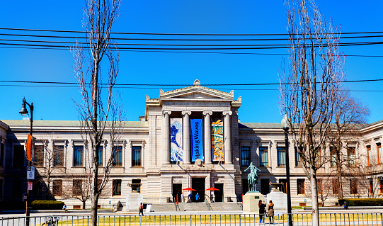 Boston, Massachusetts, USA - March 29, 2023: The Museum of Fine Arts (abbreviated as MFA Boston or MFA) is an art museum in Boston. It is the 20th-largest art museum in the world, measured by public gallery area. It contains 8,161 paintings and more than 450,000 works of art, making it one of the most comprehensive collections in the Americas. Founded in 1870 in Copley Square, the museum moved to its current Fenway location in 1909. View from across Huntington Avenue of the Museum entrance.
