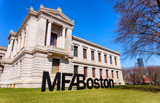Boston, Massachusetts, USA - March 29, 2023: The Museum of Fine Arts (aka MFA Boston or MFA) is an art museum in Boston. It is the 20th-largest art museum in the world, measured by public gallery area. It contains 8,161 paintings and more than 450,000 works of art, making it one of the most comprehensive collections in the Americas. Founded in 1870 in Copley Square, the museum moved to its current Fenway location in 1909. Large lawn sign in front of MFA building.