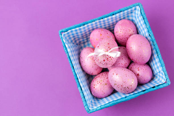 istock Easter. Pink Easter eggs in a basket on a trendy lilac background. Happy easter. holidays. top view 1478913567