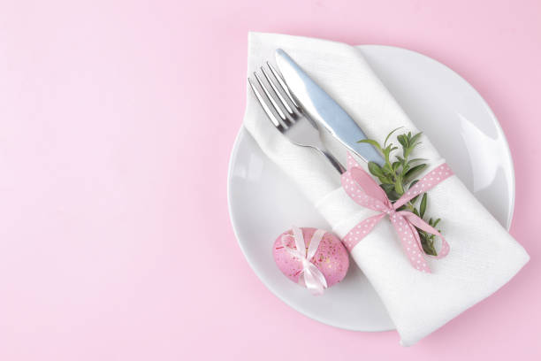 istock Easter. Pink Easter eggs and plate, knife and fork on a trendy pink background. Easter table setting. Happy easter. holidays. top view 1478913583