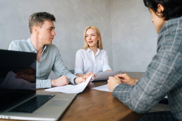 visão de baixo ângulo de conselheiros sérios de gerentes de rh entrevistando jovens do sexo masculino no cargo. os empregadores que realizam curriculum vitae falam sobre o cara candidato. - job search note pad business person interview - fotografias e filmes do acervo