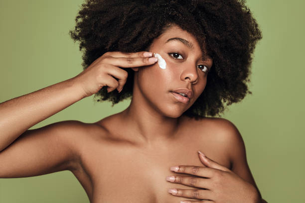 istock Young ethnic lady with perfect skin applying cream on face 1478914057