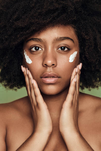 istock Black woman applying cream on face 1478914065