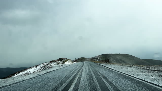 Car moves along an asphalt road during a snow storm.