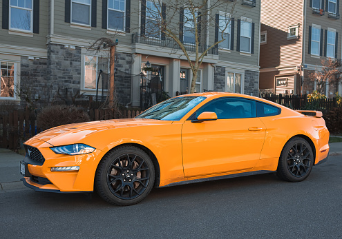 Orange muscle car Ford Mustang at the countryside. Front headlights of orange modern car on a street. Nobody, street photo, editorial-January 30,2023-Surrey Canada