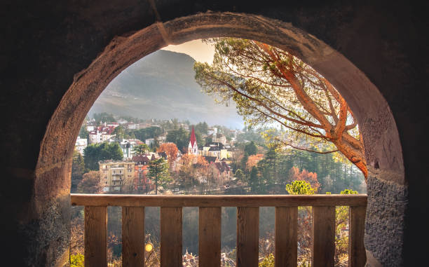 verträumtes stadtbild in warmen herbstmorgenlichtern durch balkon steinbogenhintergrund - merano stock-fotos und bilder