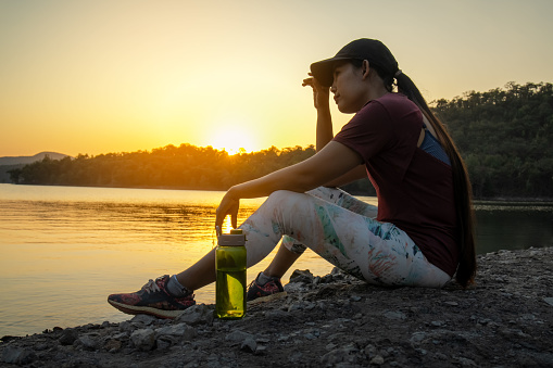 Silhouette of young woman drinking water after exercise, fitness health concept