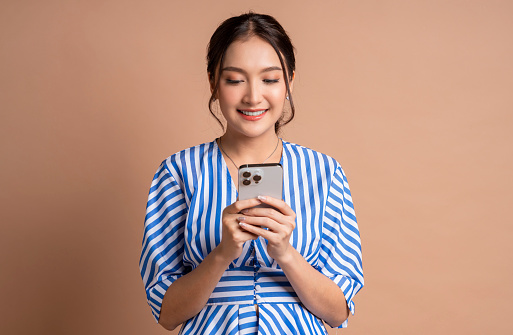 delightful asian female woman casual cloth dress hand using smartphone text conversation communication talking to her friend with happiness positive face expression,woman use cellphone studio shot