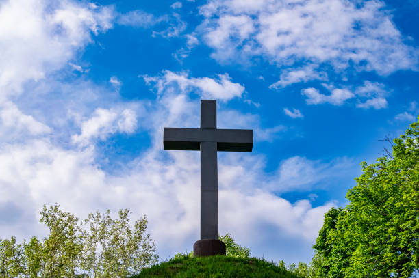 istock Christian cross on a mound against a blue sky with white clouds. 1478939642