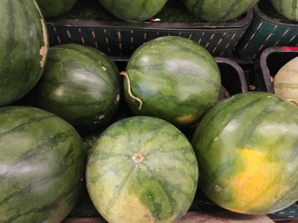 Photo of Some big sweet green watermelons for sale. Basket of watermelons in the market