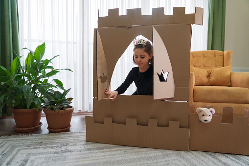 Cute little girl dressed up as a princess while playing with handmade castle