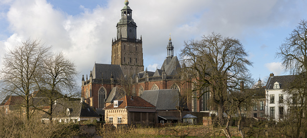 Picturesque winter cityscape panorama of medieval Hanseatic city Zutphen in The Netherlands with soft blue sky and cloud formation lit up by afternoon