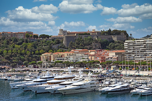 Wide angle view of the Port Hercules harbour of  Monaco Monte Carlo. In the background overlooking the harbour is the Rock of Monaco where Monaco-Ville, the oldest part of Monaco, and the Prince's Palace can be seen against the skyline of a clear blue sky, together with the many high-rise apartment buildings climbing the hillside
