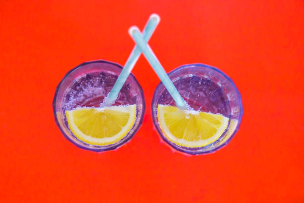istock Two glasses with drink and lemon part on red background top view 1478971175