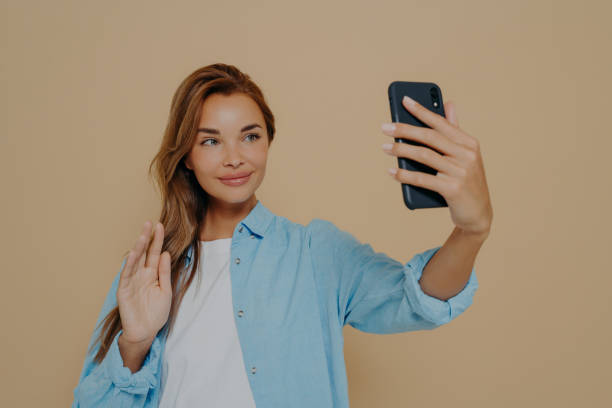 istock Cheerful lady waving at camera on beige background 1478972111