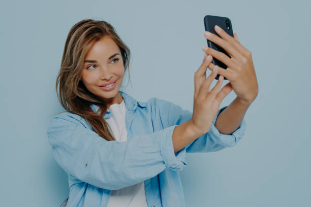 istock Attractive blogger taking selfie near light blue wall 1478972163