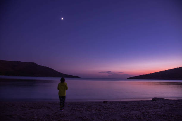 istock Person in darkness looking at moon on the beach 1478978595