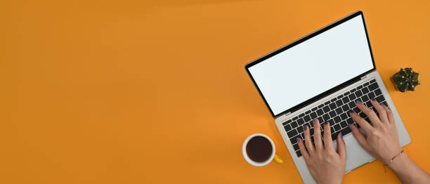 istock Above view of male designer's hands painted nails using a empty screen of laptop computer on the yellow background. 1478979297