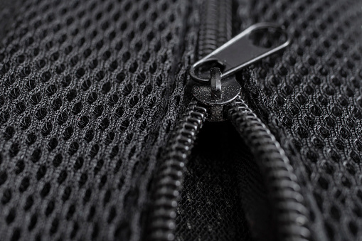 zipper on synthetic black mesh, soft focus close up