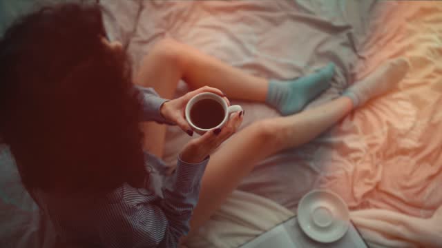 pretty brunette woman in morning bed with books and coffee