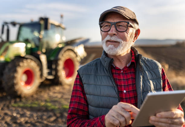 istock Senior farmer with tablet in field with tractor in background 1479011273