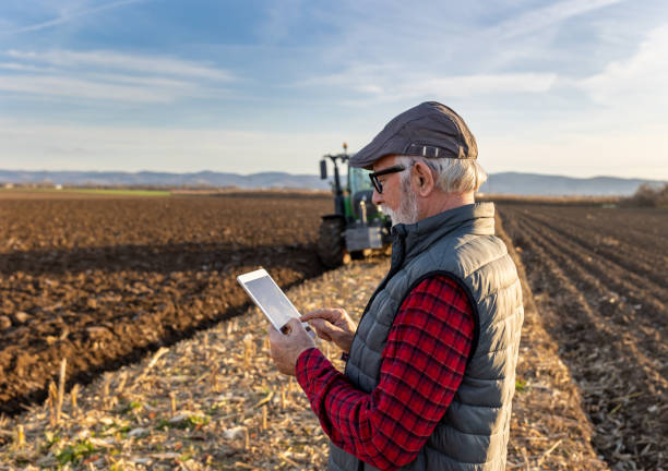 istock Senior farmer with tablet in field with tractor in background 1479011400