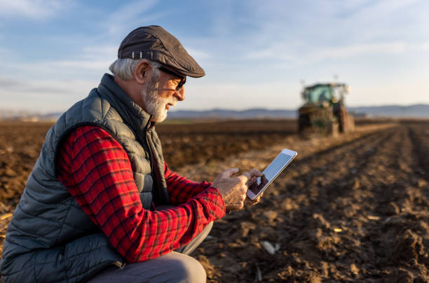 istock Senior farmer with tablet in field with tractor in background 1479011420