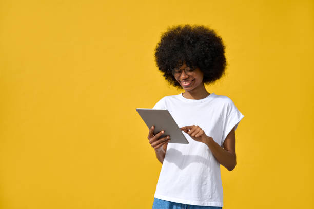 istock A woman using tablet in her hand and enjoy applications on yellow background 1479014328