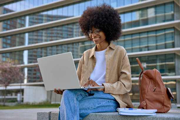 istock A happy young woman using laptop while sitting in front of buildings. 1479014351