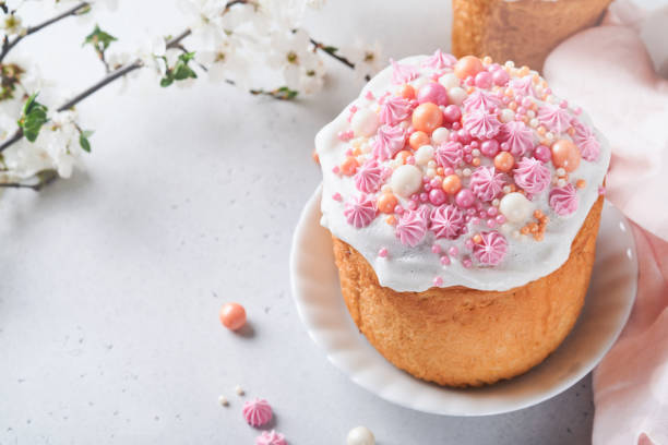 istock Traditional Easter sweet bread or cakes with white icing and sugar decor, colored eggs and cherry blossom tree branch over white table. Various Spring Easter cakes. Happy Easter day. Selective focus. 1479014519