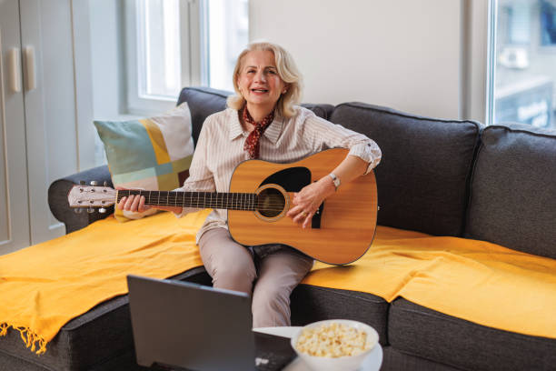 istock A beautiful older woman is using online tutorials to learn to play an acoustic guitar at home. 1479014891