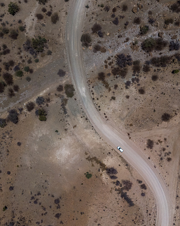 An aerial view of a car driving along a winding road in a desert