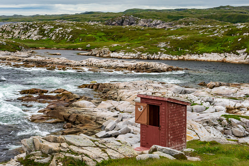 Red outhouse on rocky shoreline, Rose Blanche, Newfoundland and Labrador, Canada.