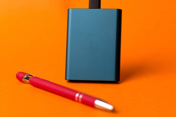 istock External SSD disk and a red pen isolated on an orange background 1479028301
