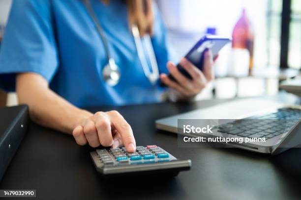 Healthcare Costs And Fees Concepthand Of Smart Doctor Used A Calculator And Smartphone Tablet For Medical Costs At Hospital In Morning Light Stock Photo - Download Image Now