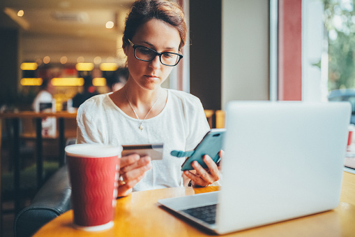 Woman in a cafe having problems with the credit card