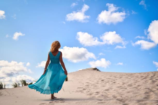 bella donna bionda sulla sabbia calda con il cielo blu sullo sfondo. - vogue 40th foto e immagini stock