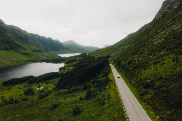 vista aérea do carro dirigindo a estrada ao longo da terra cênica de lagos em colinas verdes na noruega - more objects - fotografias e filmes do acervo