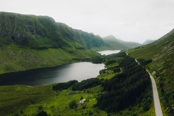 vista aérea da estrada ao longo da terra cênica dos lagos em colinas verdes na noruega - more objects - fotografias e filmes do acervo